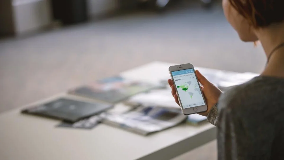 Hand hält ein Smartphone mit Weltkarte – Reise-eSIM T-Travel